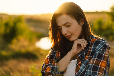 Woman closed her eyes, praying in a field during beautiful sunset.の写真素材