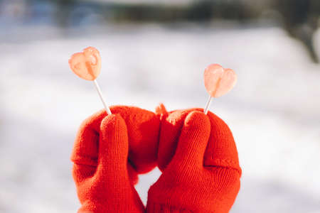 Valentines day card. Woman in red mittens holding two heart shaped lollipops. I love Youの写真素材
