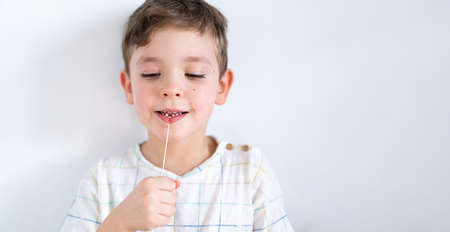 Cute boy pulling loose tooth using a dental floss. Process of removing a baby tooth.