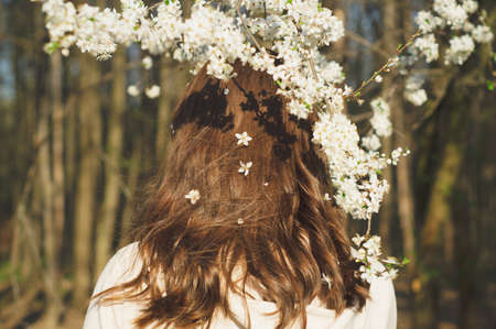 Young beautiful woman among flowering trees. Back view. Spring conceptの写真素材
