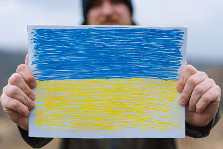 Ukrainian man holds a painted flag of Ukraine. War of Russia against Ukraine.の写真素材