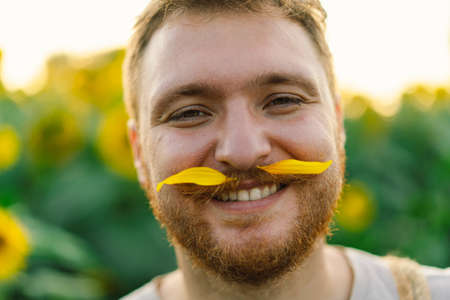 Man with yellow flowers in mustache. Breathe free. A man has fun in nature.の写真素材