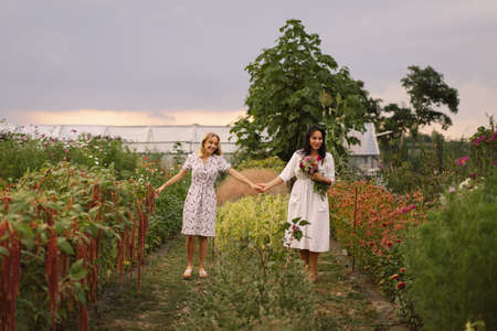 A young mother with a teenage daughter spends time in the garden. Family holiday and togetherness.の写真素材