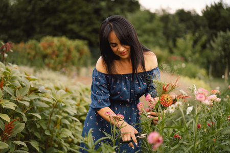 A Young woman prune flowers in a floristic flower farm. Woman florist.の写真素材