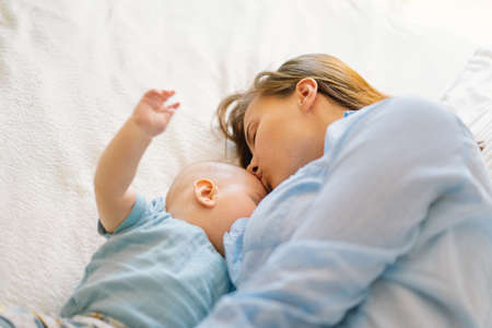Newborn baby boy sucking milk from mothers breast.