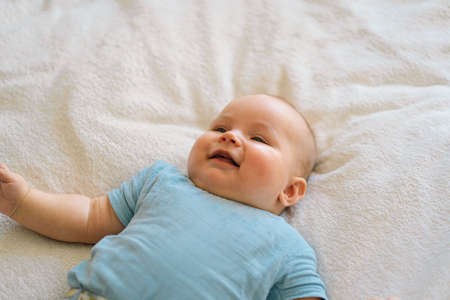 Cute newborn little baby boy in bed. Baby goods packaging template.の写真素材