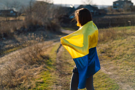 Woman holding a yellow and blue flag of Ukraine in outdoorsの写真素材