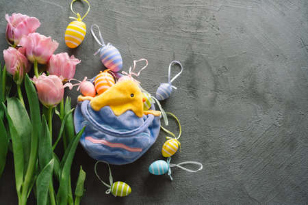 Spring tulips and multicolored Easter eggs on a wooden background.