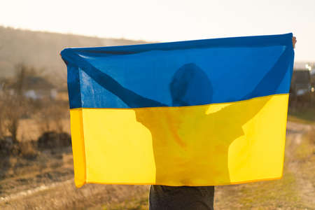 Woman holding a yellow and blue flag of Ukraine in outdoors