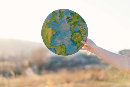 Woman holding planet in hands against green spring background. Earth dayの写真素材