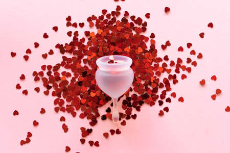 Silicone menstrual cup. Womens health and alternative hygiene. Cup with little red hearts