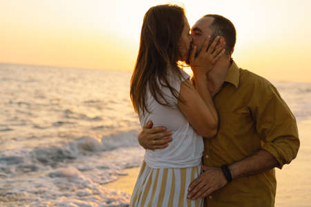 Young romantic couple dancing turning around by sea. Seascape at sunset with beautiful skyの写真素材