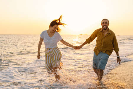 Young romantic couple dancing turning around by sea. Seascape at sunset with beautiful skyの写真素材