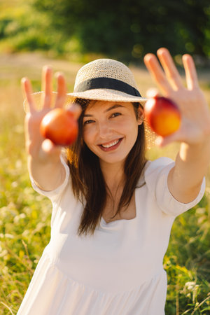 Happy carefree summer girl in outdoor field with orange peach fruit.の写真素材