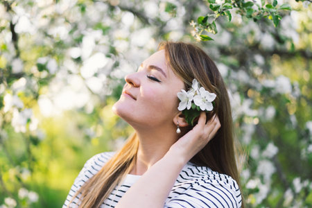 Beautiful young woman with spring flowers enjoying nature and laughing on spring garden.の写真素材
