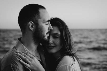 Black and white photo. Young romantic couple dancing turning around by sea.の写真素材
