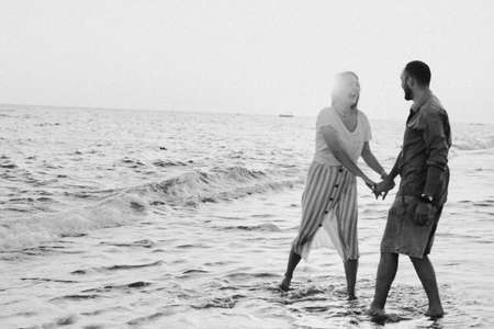 Black and white photo. Young romantic couple dancing turning around by sea.