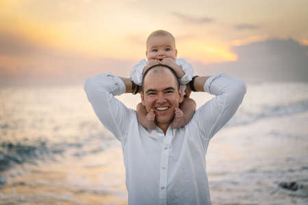Father and baby play on the beach. Dad and him Child together enjoying sunset.の写真素材