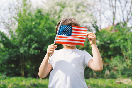 Happy little patriotic boy holding American flag.の写真素材