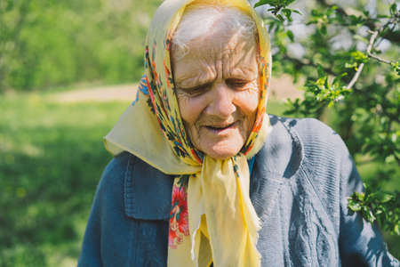 Portrait of an old happy woman in a yellow headscarf.の写真素材