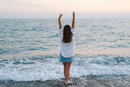Portrait of a young woman dancing turning around by sea. People from behindの写真素材