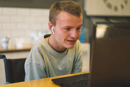 Handsome young invalid disabled man talking on mobile phone in kittchen. Person with disabilitiesの写真素材