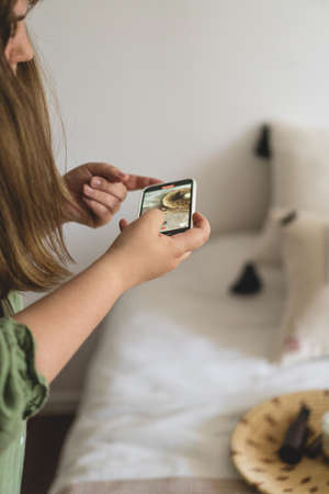 A young woman is filming home goods for her online store on her phone camera.の写真素材