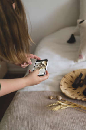 A young woman is filming home goods for her online store on her phone camera.の写真素材