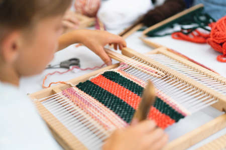Girl weaving small rug with pattern at masterclass on weaving.の写真素材