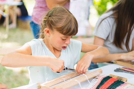 Girl weaving small rug with pattern at masterclass on weaving.の写真素材