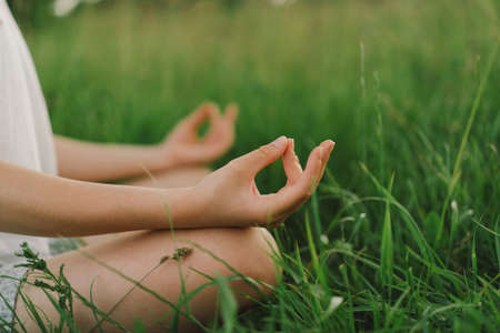 Girl in a white T-shirt doing yoga in a beautiful field. Healthy lifestyle and mindfulness conceptの写真素材