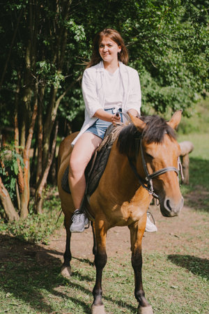 Beautiful woman rides a horse. Controlling the horse with the reinsの写真素材