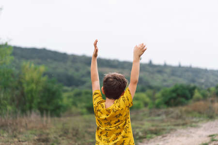 A six-year-old boy is standing with his back in the countryside. Back view.の写真素材