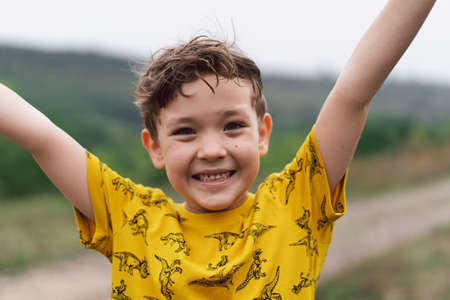A six year old boy smiles at the camera in the parkの写真素材