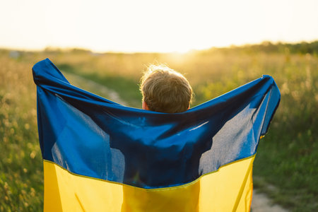 Ukrainian child boy in white t shirt with yellow and blue flag of Ukraine in field.の写真素材