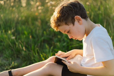 Christian boy holds bible in her hands. Reading the Holy Bible in a field during beautiful sunsetの写真素材