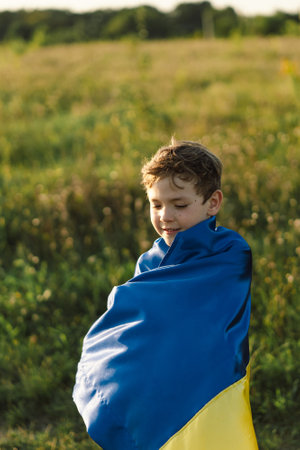 Ukrainian child boy in white t shirt with yellow and blue flag of Ukraine in field.の写真素材