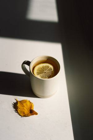 Flat lay of pumpkins, dried leaves, accessories and tea with lemon in cup on wooden background.の写真素材