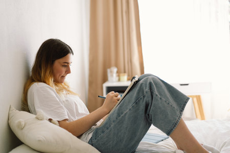 A teenage girl is drawing or doing homework in the bedroom. A teenager studies at home.