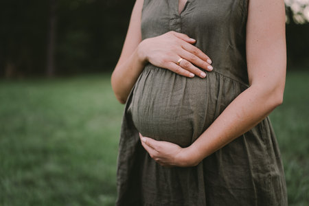 A beautiful pregnant woman outdoors, happily expecting a baby and a happy time of pregnancyの写真素材