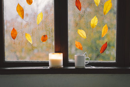 Still life details in home on a wooden window. Sweater, candle, hot tea and autumn decorの写真素材