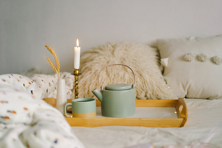 Cup of tea and teapot on a serving tray on a bed.の写真素材