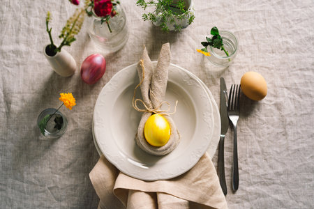 Happy Easter. Stylish easter eggs on a napkin with spring flowers on white wooden backgroundの写真素材