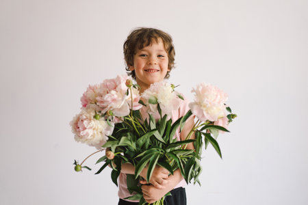 Cheerful happy child with Peonys bouquet. Smiling little boy on white background.の写真素材