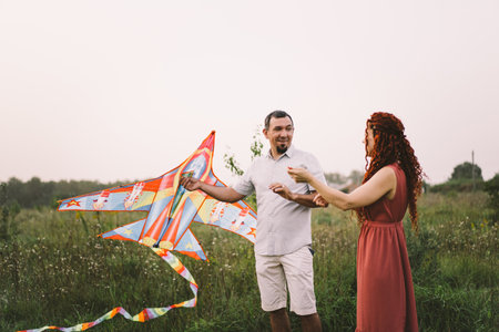 Happy family and children run on meadow with a kite in the summer on the nature.の写真素材