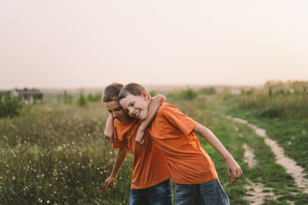 Funny twin brother boys playing outdoors on field at sunset.の写真素材