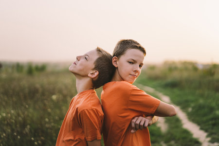Funny twin brother boys playing outdoors on field at sunset.の写真素材