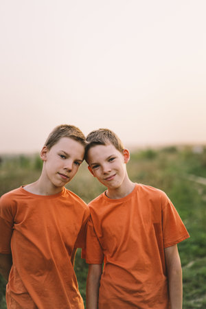 Funny twin brother boys playing outdoors on field at sunset.の写真素材