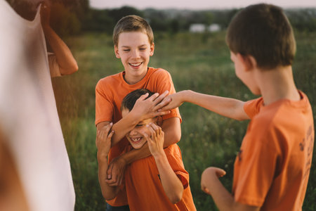 Funny boys brothers in a orange T-shirt playing outdoors on the field at sunsetの写真素材