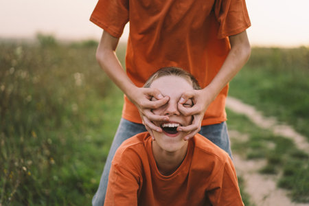 Funny twin brother boys playing outdoors on field at sunset.の写真素材